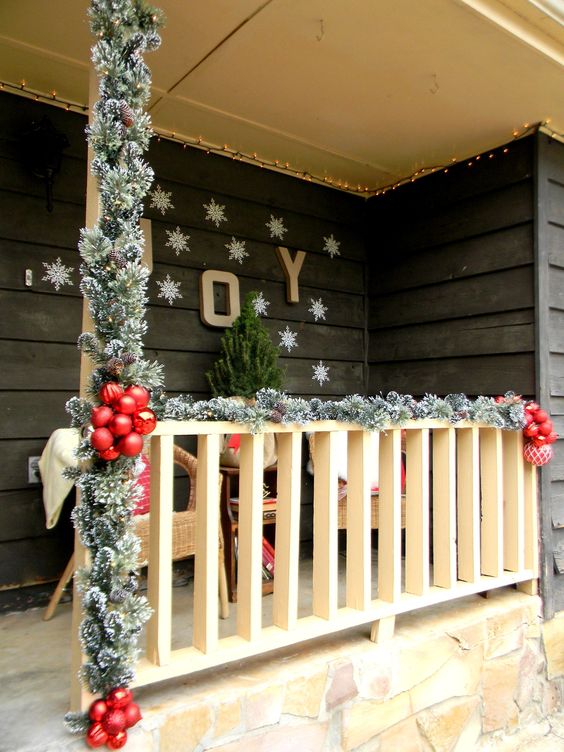 faux evergreen banister decor, red ornaments and snowflakes on the wall