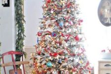 a super bold tree decorated with lots of colorful ornaments, lights and ribbons and in a zinc bucket for a rustic vintage look