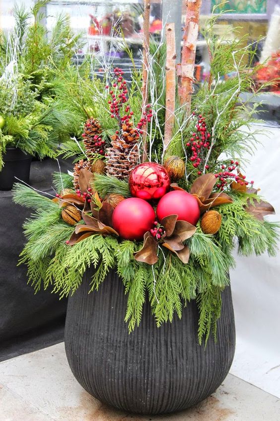 a large urn, evergreens, pinecones, berries, leaves and oversized ornaments