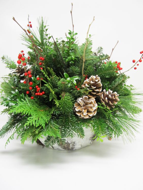 a bark wrapped centerpiece with evergreens, branches, berries and pincones
