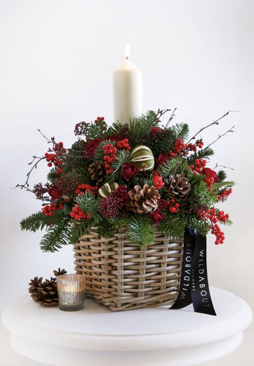a basket arrangement with pinecones, berries and evergreens