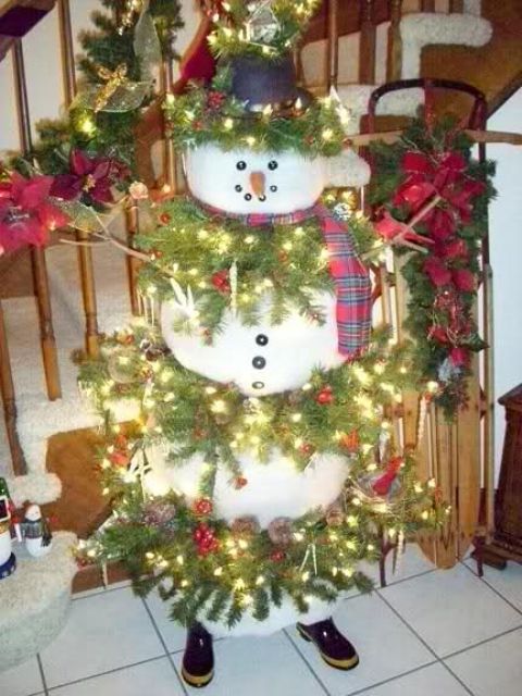 large snowman with fir branches and lights