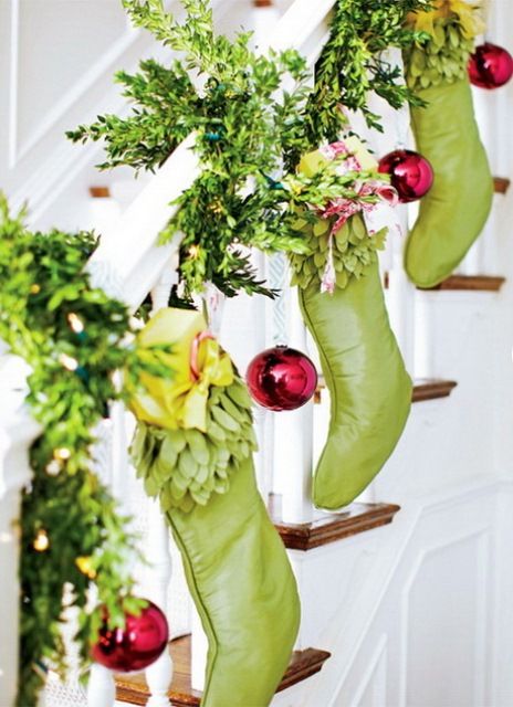 greenery garland wrapping around the banister and green stockings