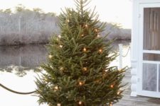 vintage lights and burlap-wrapped tree base are a cool combo for an outdoor Christmas tree or as an all-natural style idea for the tree
