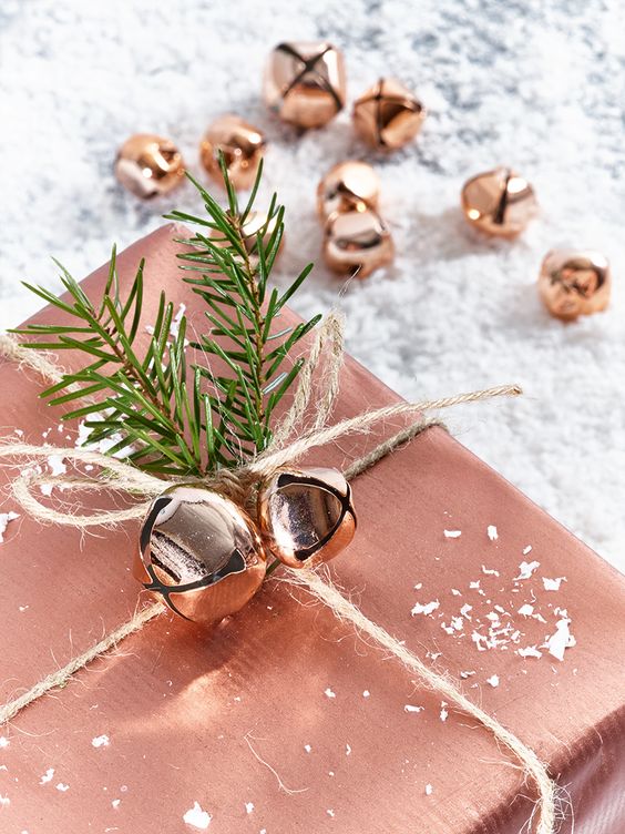 copper gift wrapping and jingle bells and evergreen sprigs for decor