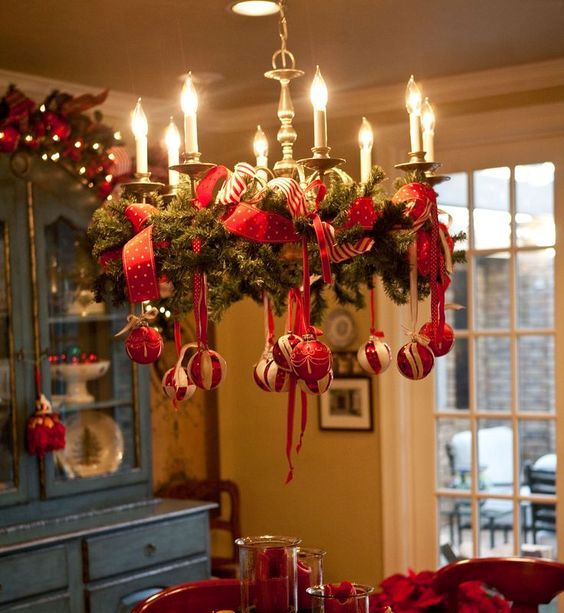 decorate a usual chandelier with evergreen branches, red ribbon and ornaments