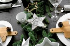 25 a table setting with faux evergreens, star-shaped candle holders and pinecones