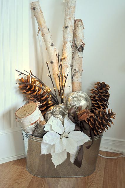 a galvanized bucket with branches, pinecones, ornaments and a poinsettia