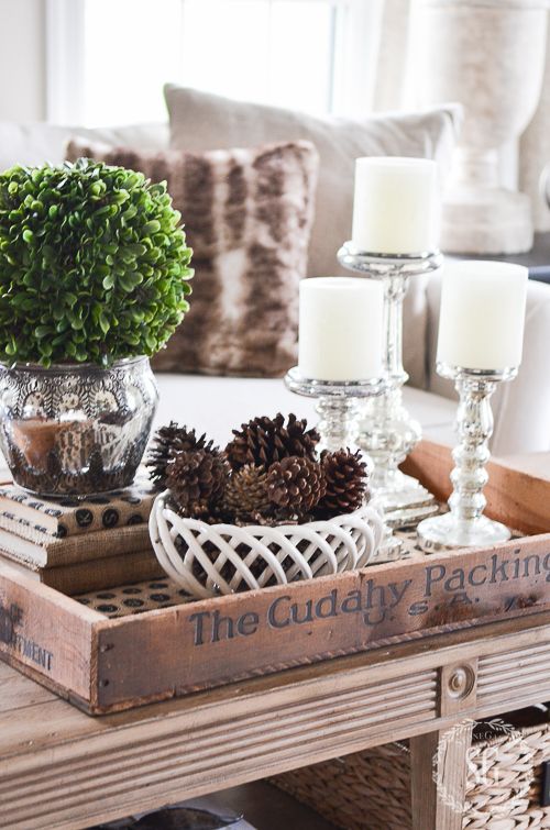 neutral coffee table decor with pinecones, greenery and candles