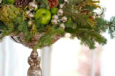 28 a silver stand with oraments, pinecones, evergreens and ggreen apples