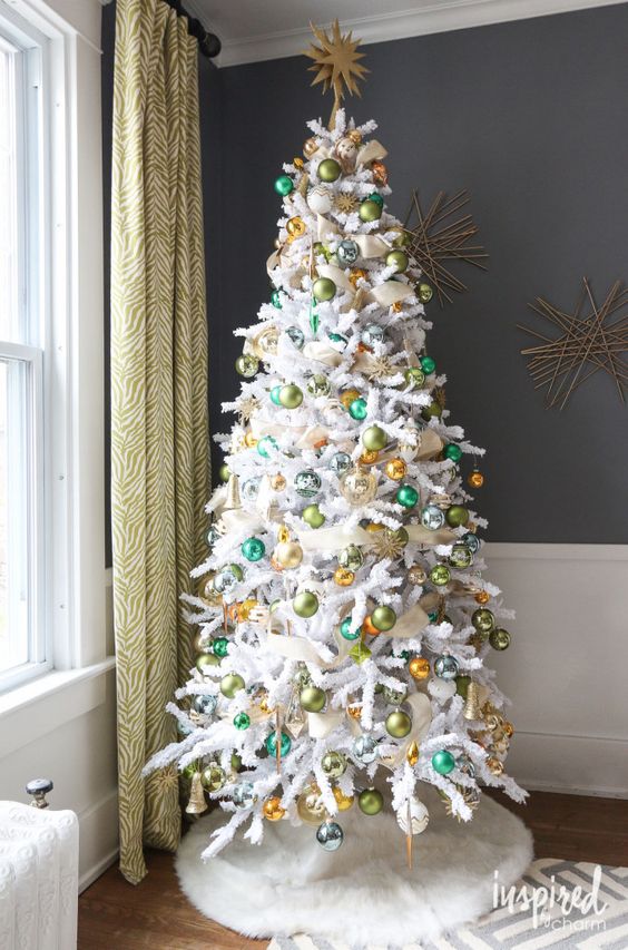 a white Christmas tree styled with colorful ornaments and a white faux fur tree skirt looks absolutely luxurious