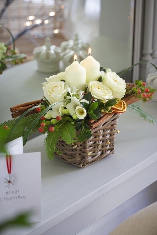 a tiny basket arrangement with candles, flowers and cinnamon sticks