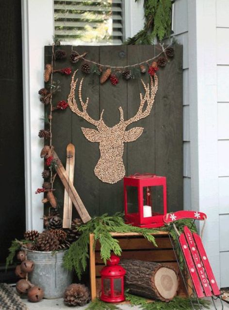 a rustic setup with a crate, a sleigh, a lantern and pinecone decor