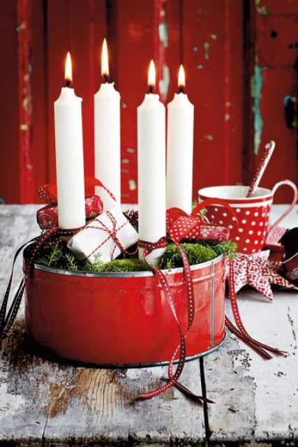 red tin filled with white candles, moss and small gift packs