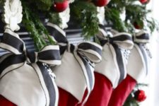 32 simple red stocking with a white cuff, decorated with striped charcoal and white ribbon, and evergreen sprigs