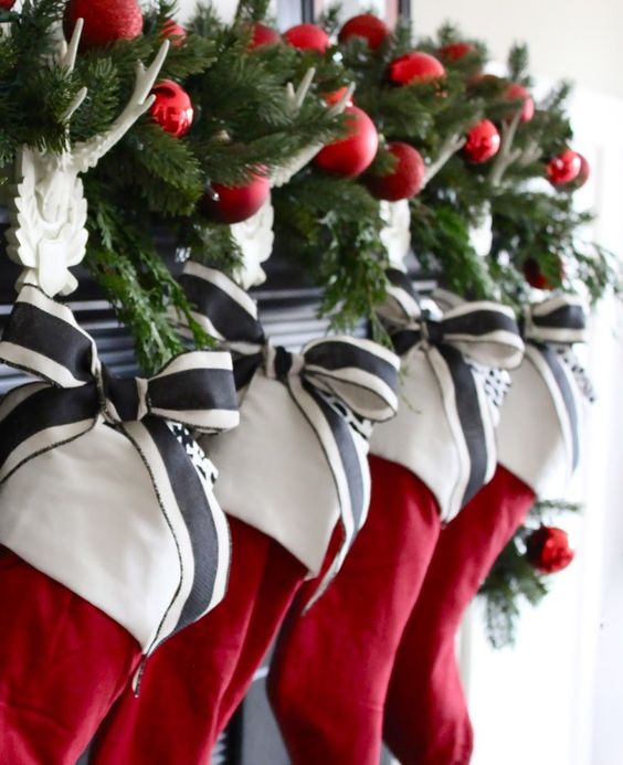 simple red stocking with a white cuff, decorated with striped charcoal and white ribbon, and evergreen sprigs