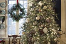 a whimsical Christmas tree decorated with branches, pinecones, white ornaments and withvintage urn for a chic and refined touch