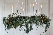 a Christmas chandelier of greenery and evergreens, twigs and candles is a beautiful and all-natural holiday decor idea