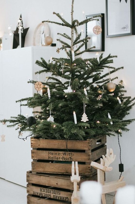 a Nordic Christmas tree with lights, porcelain and wooden ornaments and with old crates cover the tree base