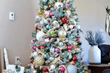 a beautiful and bright Christmas tree decorated with lights, greenery and bright ornaments is wow