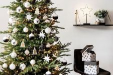 a beautiful modern Christmas tree with lights, black, white and stained plywood ornaments is a very chic idea suitable for a Nordic space