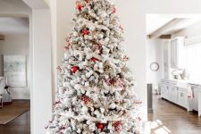a chic Christmas tree with red and white ornaments, ribbons and branches on top is a cool decor idea for the holidays