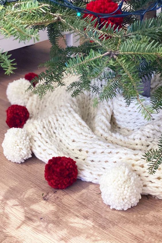 a chunky knit Christmas tree with red and white pompoms is a cool and catchy idea for styling a traditional Christmas tree