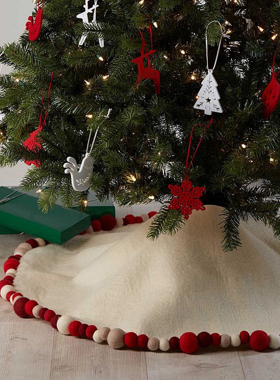 a creamy Christmas tree skirt with colorful pompoms that matches the Christmas tree decor in the best way possible