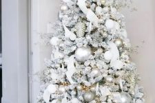 a dreamy flocked Christmas tree with silver and white ornaments, branches, ribbons and lights is an amazing idea