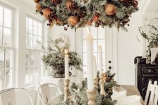 a fantastic wreath Christmas chandelier of evergreens, pinecones and faux apples is a cool and catchy idea