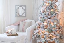 a flocked Christmas tree with lights, pastel ornaments on a stand is a chic and glam idea to rock