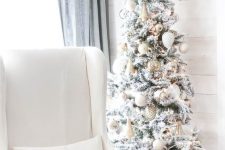 a flocked Christmas tree with oversized metallic ornaments, lights and bells is a lovely glam decor idea for the holidays