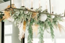 a frame chandelier with evergreens, dried blooms, mint and silver ornaments is a fresh and cool decoration for the holidays