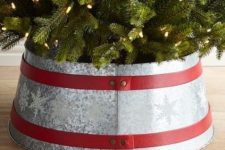 a galvanized metal tree collar with snowflakes and red ribbons on the whole diameter