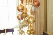 a glam crystal chandelier decorated with gold, silver and red glitter ornaments is a chic and cool idea for Christmas