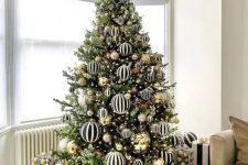 a jaw-dropping modern Christmas tree decorated with black and white striped and gold large-scale ornaments is amazing