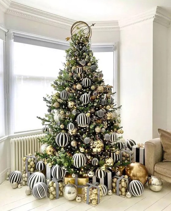 A jaw dropping modern Christmas tree decorated with black and white striped and gold large scale ornaments is amazing