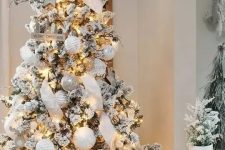 a jaw-dropping winter wonderland Christmas tree with white and silver ornaments, lights, ribbons, branches and pinecones is wow