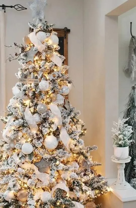 A jaw dropping winter wonderland Christmas tree with white and silver ornaments, lights, ribbons, branches and pinecones is wow