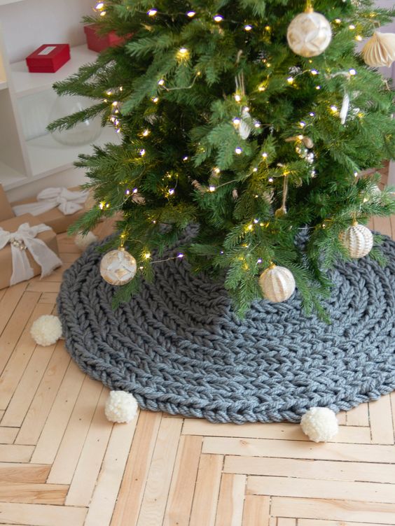 a lovely and casual Christmas tree skirt of grey chunky knit with white pompoms that echo with the baubles