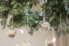 a natural holiday chandelier with greenery and clear baubles with hay is a cool and catchy decor idea to rock