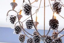 a shabby chic chandelier with crystals and snowy pinecones is a cool out of the box holiday decoration to rock