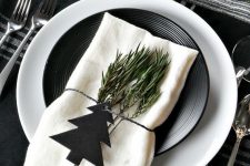a stylish black and white Scandinavian Christmas tablescape with black and white linens, plates, greenery and wooden beads is amazing