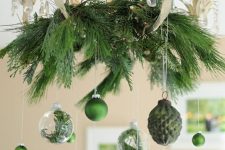 a stylish vintage floral chandelier with evergreens, green and clear ornaments with evergreens is wow