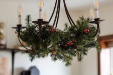 a vintage chandelier with evergreens and berries is a stylish solution for a farmhouse space during the holidays