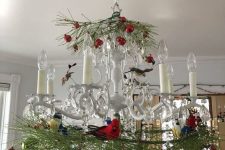 a vintage chandelier with evergreens, red and green ornaments is a chic and beautiful decor idea for the holidays
