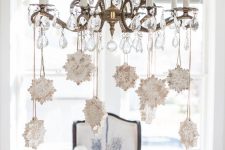 a vintage crystal chandelier with whitewashed wooden snowflakes is a cool and stylish idea to rock