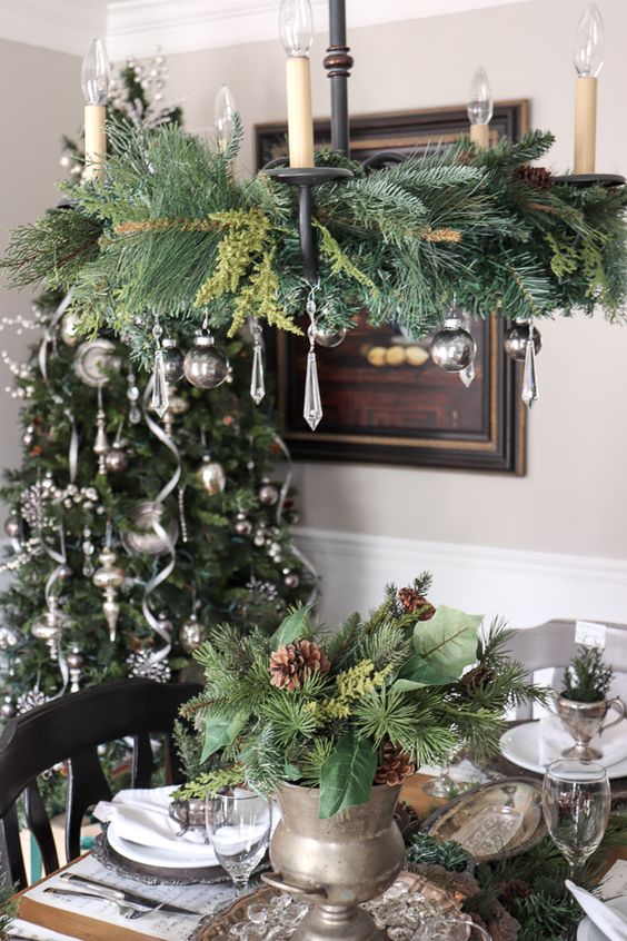 A vintage inspired Christmas chandelier with evergreens, silver ornaments and crystals is a stylish and cool idea to rock