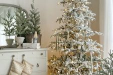 an elegant flocked Christmas tree with metallic ornaments, ribbons and lights is a cool and catchy decor idea