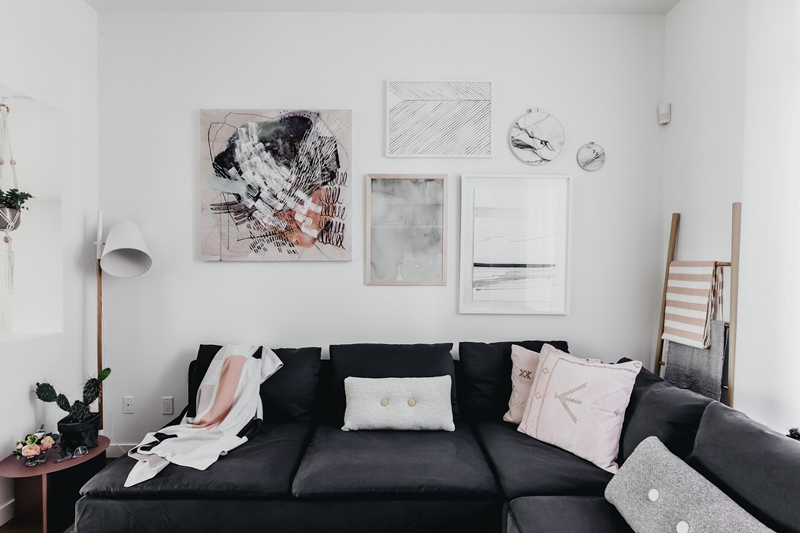 The artworks and blush pillows spruce up the Scandinavian interior of the living room